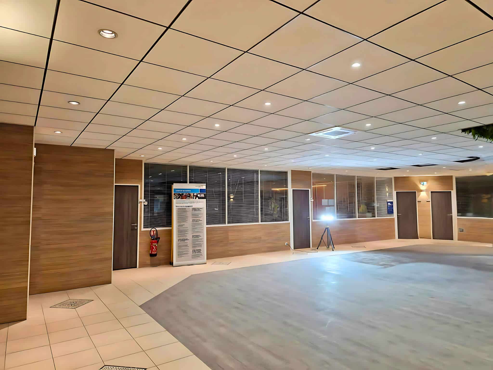 Grand hall d'accueil habillé de bois, faux plafond et éclairage intégré · chantier Vinci